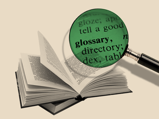 An open book and a magnifying glass focused on the word glossary.