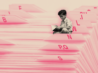 A series of labeled file folders, with a miniature boy sitting a top the M’s.
